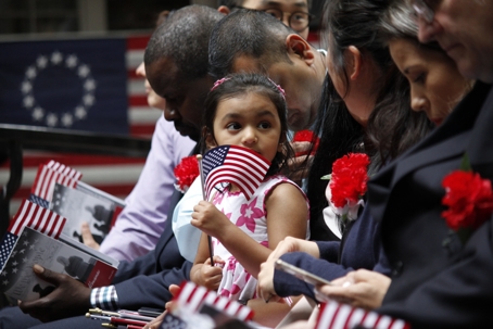 daughter of an immigrant waving American flag during oath taking ceremony